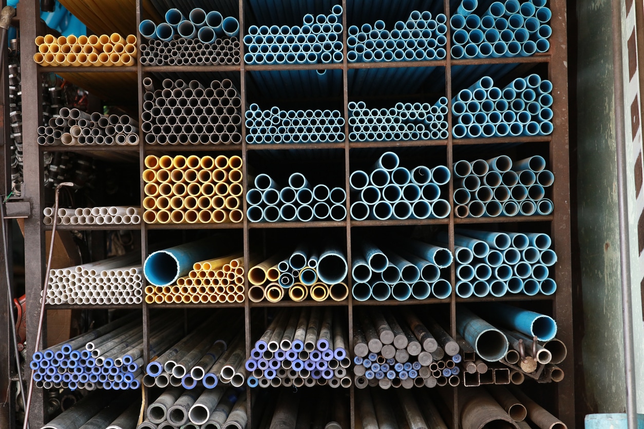 Several different types and sizes of pipes lined up on shelving.