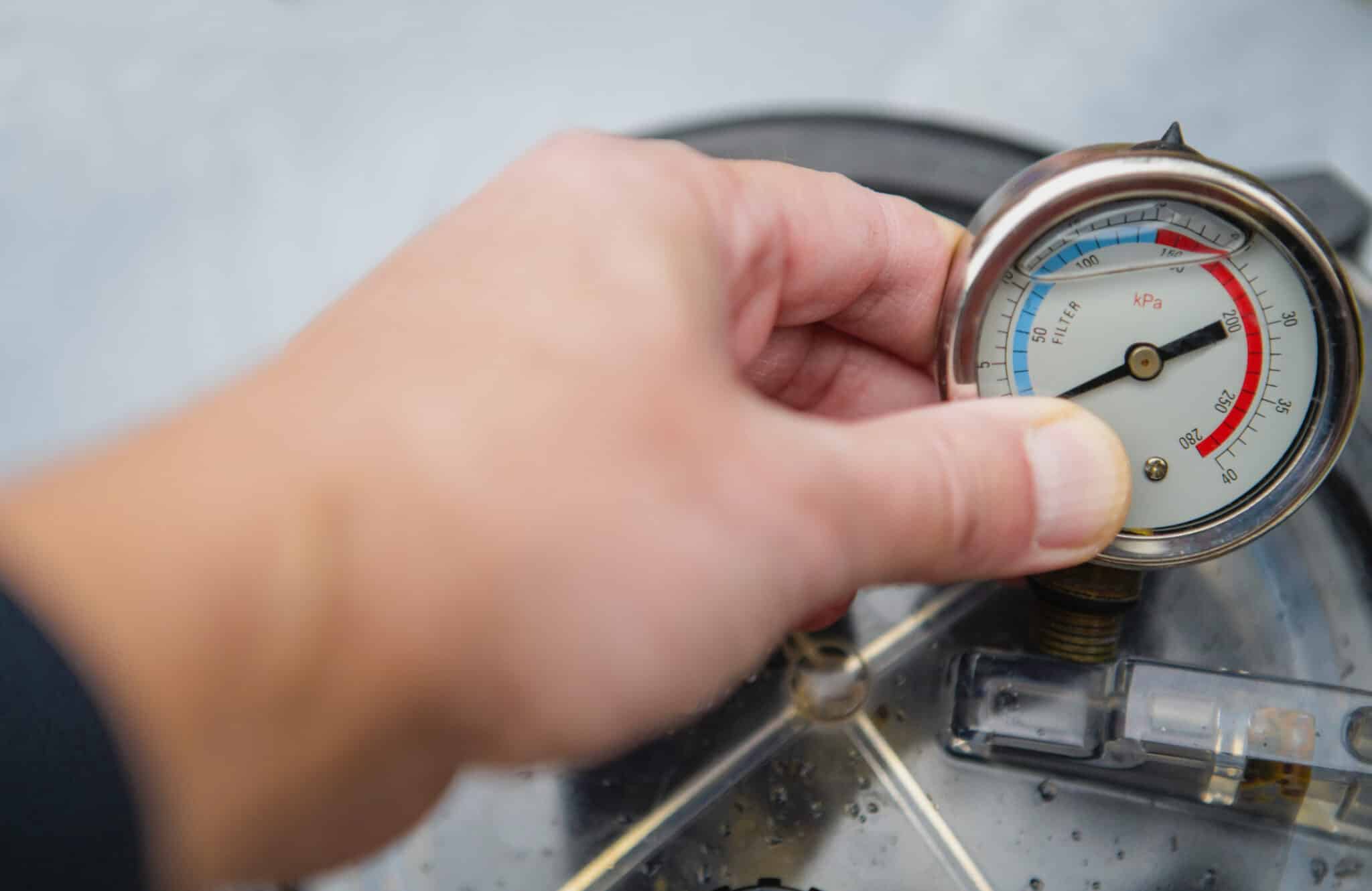 A homeowner checks a water pressure gauge after experiencing low water pressure in house appliances.