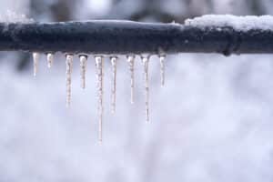 Icicles forming on a frozen pipe after a winter thaw